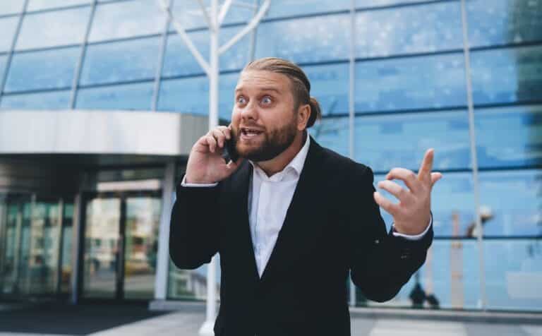 Anxious Attachment Is a Scam You’re Running on Yourself - Anxiously attached man talking on phone in amazement while making gesture