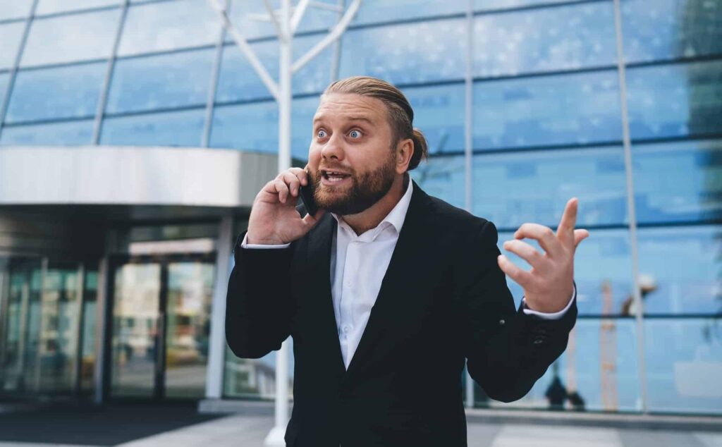 Anxious Attachment Is a Scam You’re Running on Yourself - Anxiously attached man talking on phone in amazement while making gesture