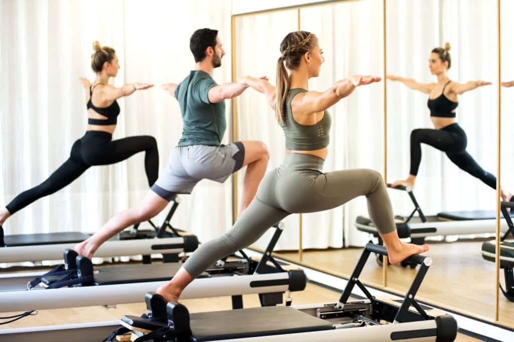 Big Dreams, Zero Follow-Through: Why Planning to Workout Feels Better Than Actually Doing It - Class in a gym doing pilates standing lunges