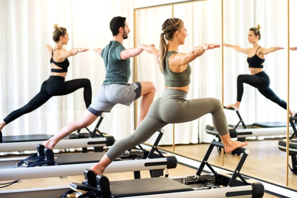 Big Dreams, Zero Follow-Through: Why Planning to Workout Feels Better Than Actually Doing It - Class in a gym doing pilates standing lunges