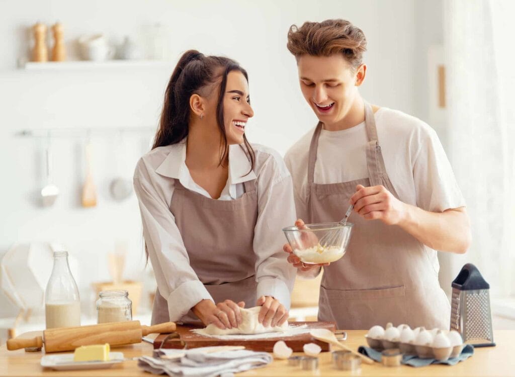 A couple baking a cake together in a bright kitchen, symbolizing the process of building healthy relationships by replacing context free boundaries with mutual understanding.