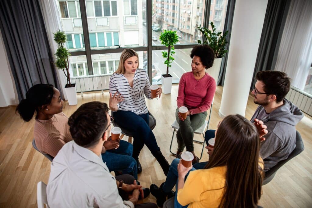 A diverse group of people seated in a circle having a discussion, symbolizing a group therapy session focused on attachment styles.