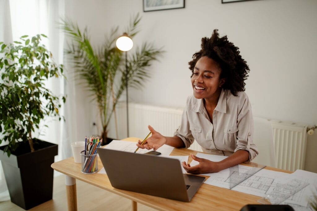 Avoidant Attachment Made Me Ghost the Therapist After She Called Me Out - Image of happy black woman, smiling while speaking or chatting on video call in office.