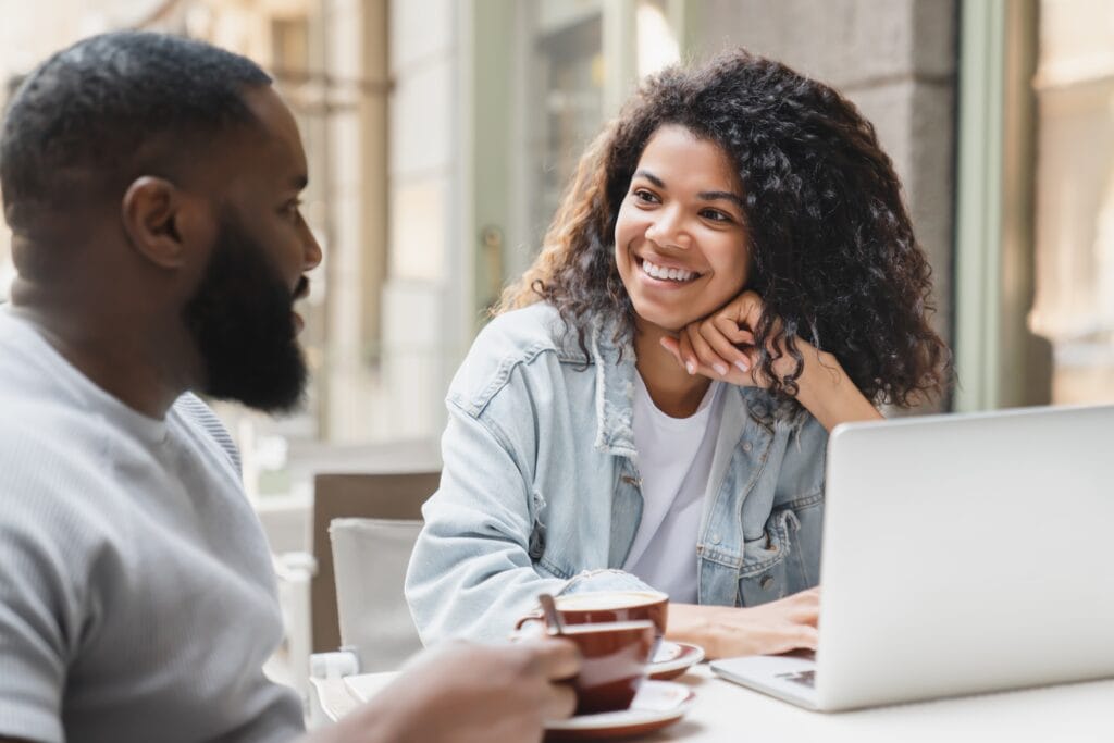 Interested young african-american couple talking communicating together in cafe