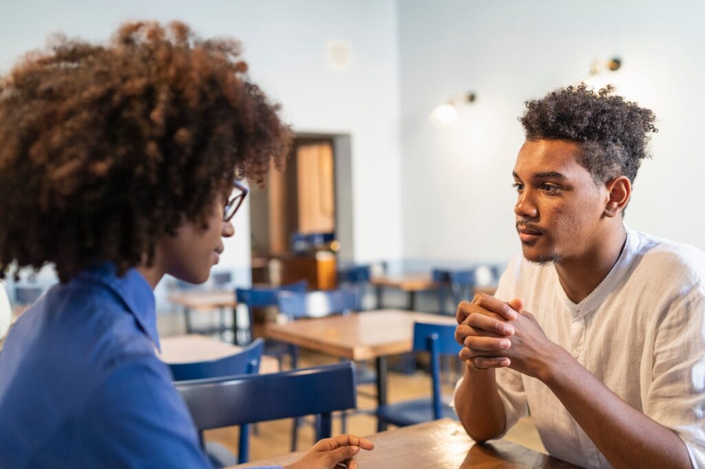 Two students sit at a café table engaged in focused discussion, illustrating the importance of collaboration, communication, and the contrast between responsive interaction and context free boundaries.