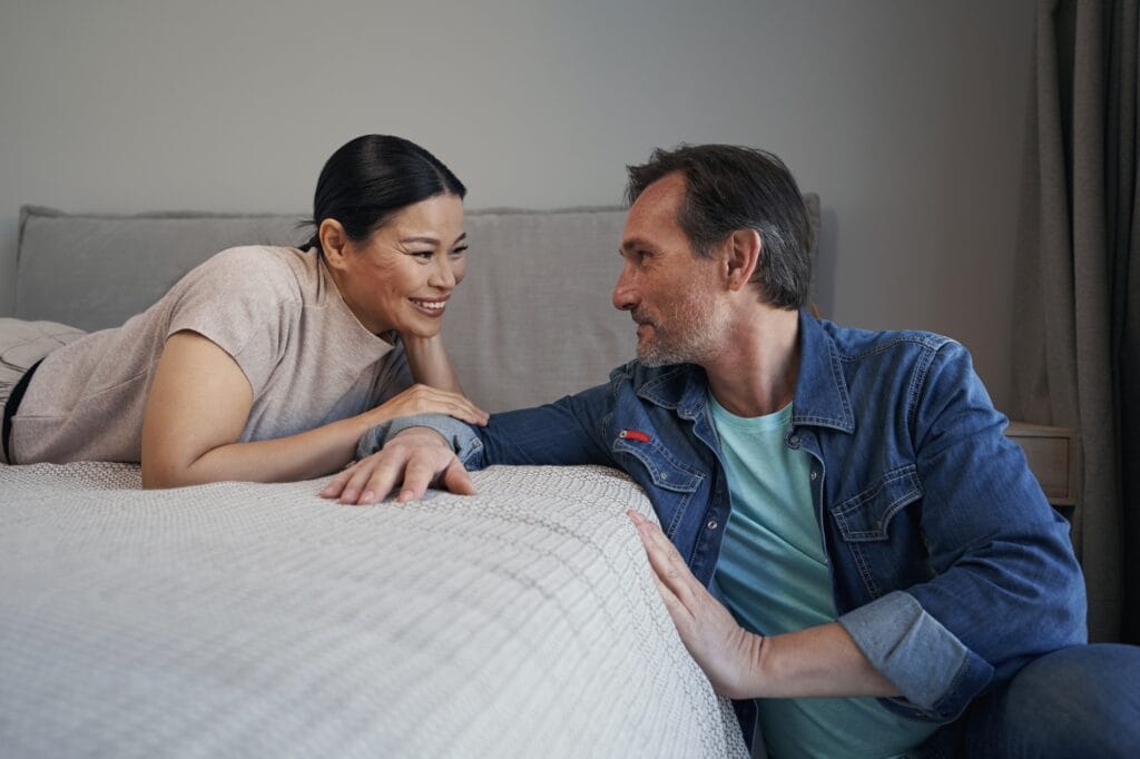 Joyful married mature couple communicating in bedroom