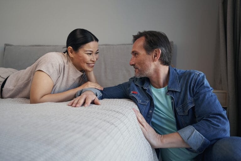 Joyful married mature couple communicating in bedroom