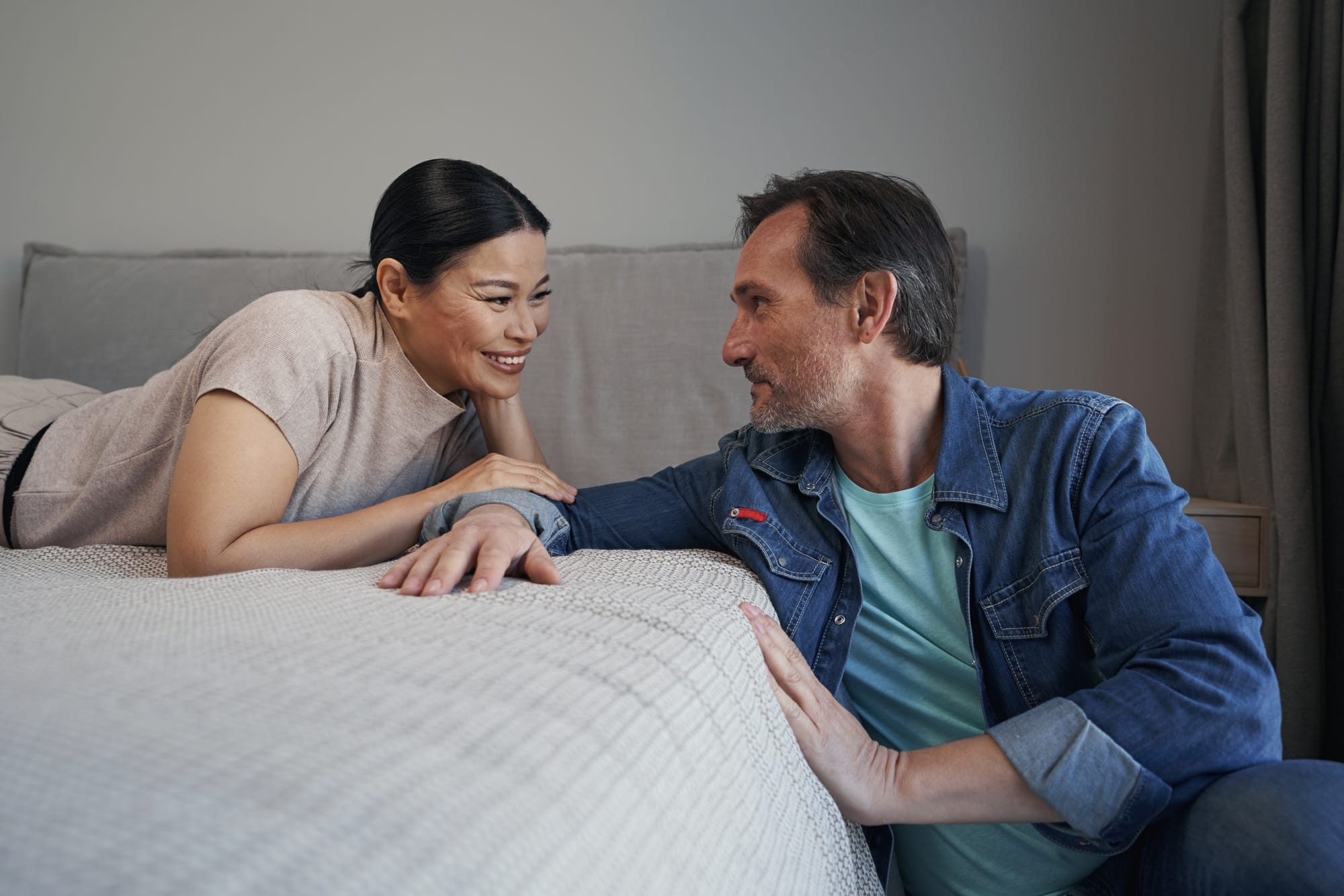 Joyful married mature couple communicating in bedroom
