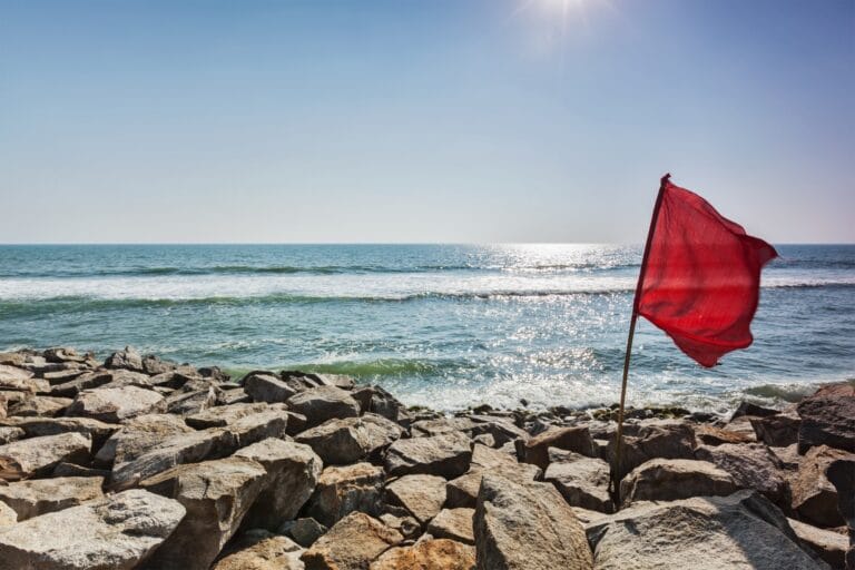 Red flag on rocky beach