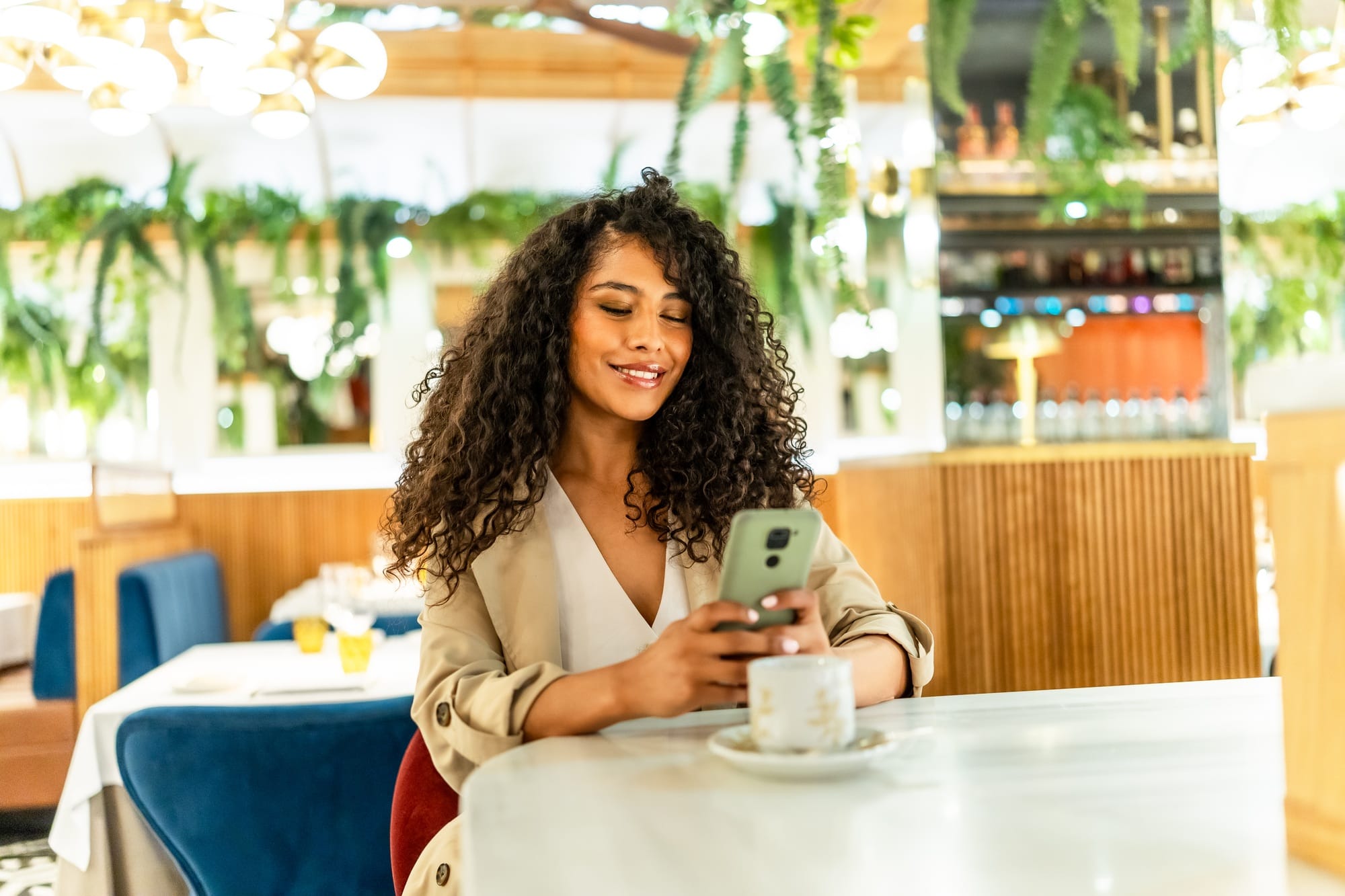Smiling woman using date app sitting on a cafeteria