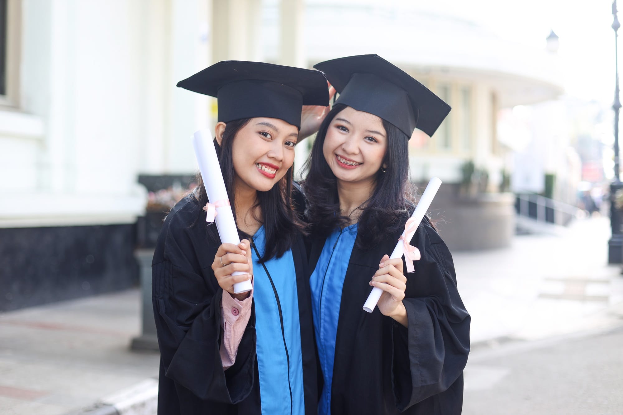 Two asian women university graduates celebrate with happiness