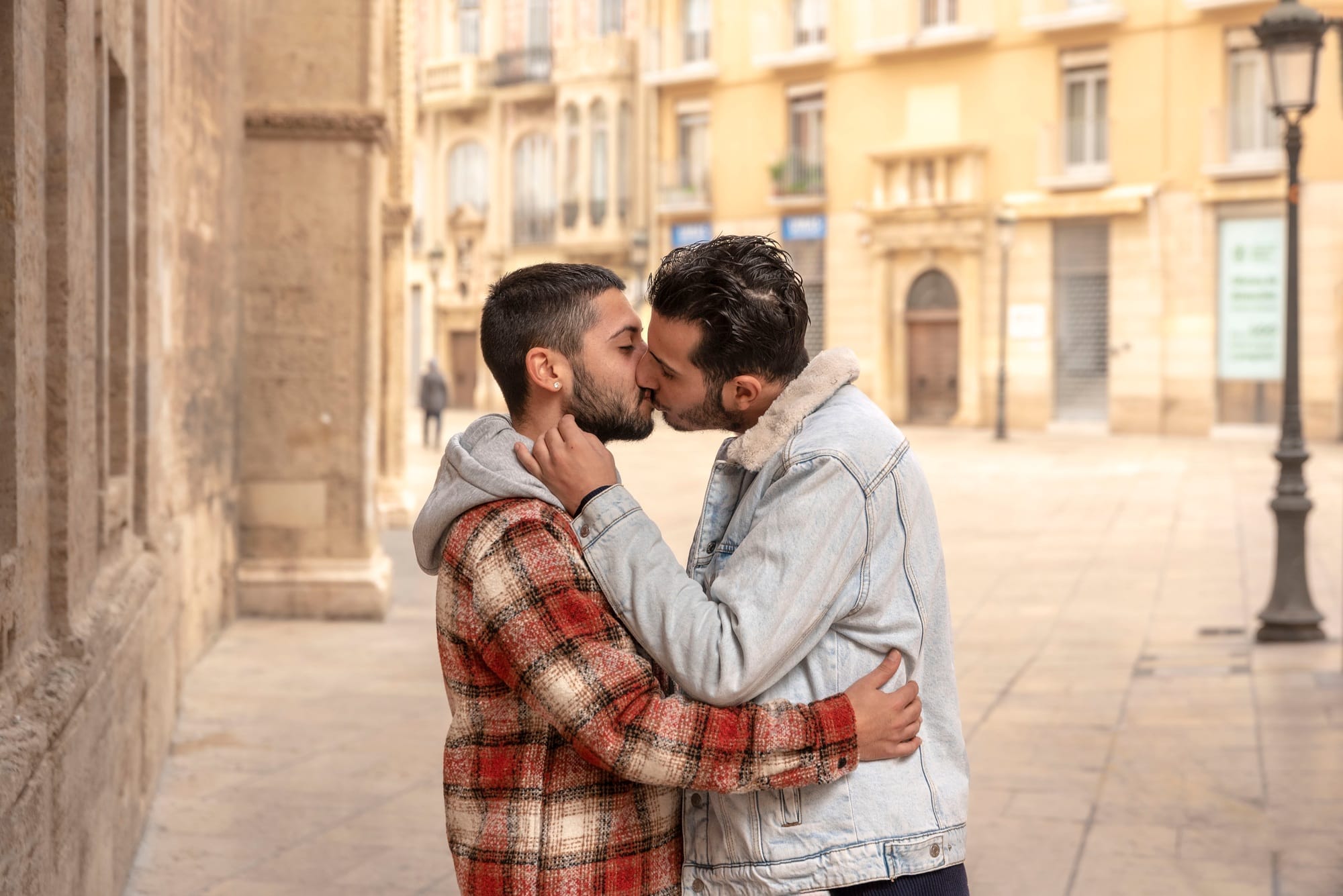 Young gay couple in love hugging and kissing in the street