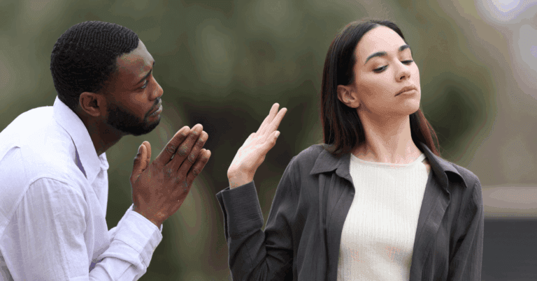 A man pleads while a woman looks away and raises her hand to dismiss him, symbolizing emotional distancing seen in fearful avoidant women.