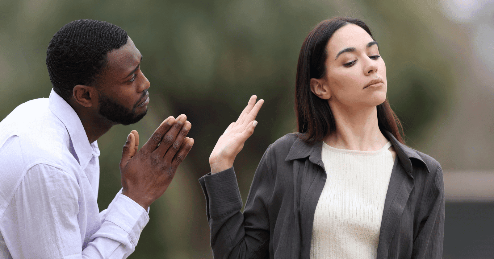 A man pleads while a woman looks away and raises her hand to dismiss him, symbolizing emotional distancing seen in fearful avoidant women.